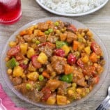 Filipino Menudo on a serving platter with plate of steamed rice in the background.