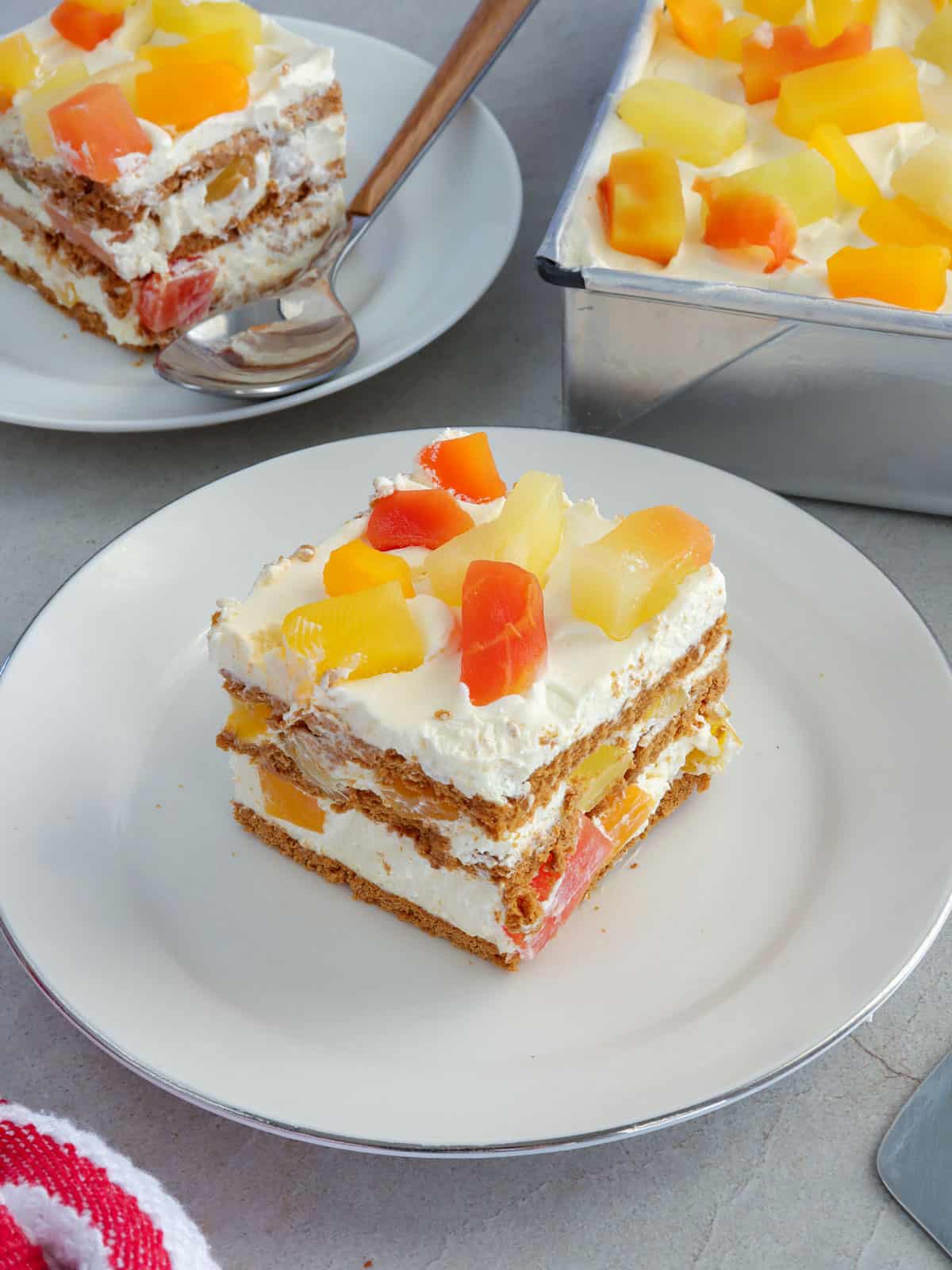 slice of no-bake fruit cocktail graham cake on a white plate.