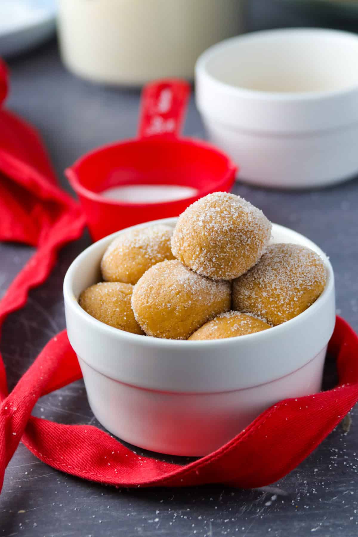 No-Cook Caramel Pastillas in a white bowl with red ribbon and red measuring cup in the background.